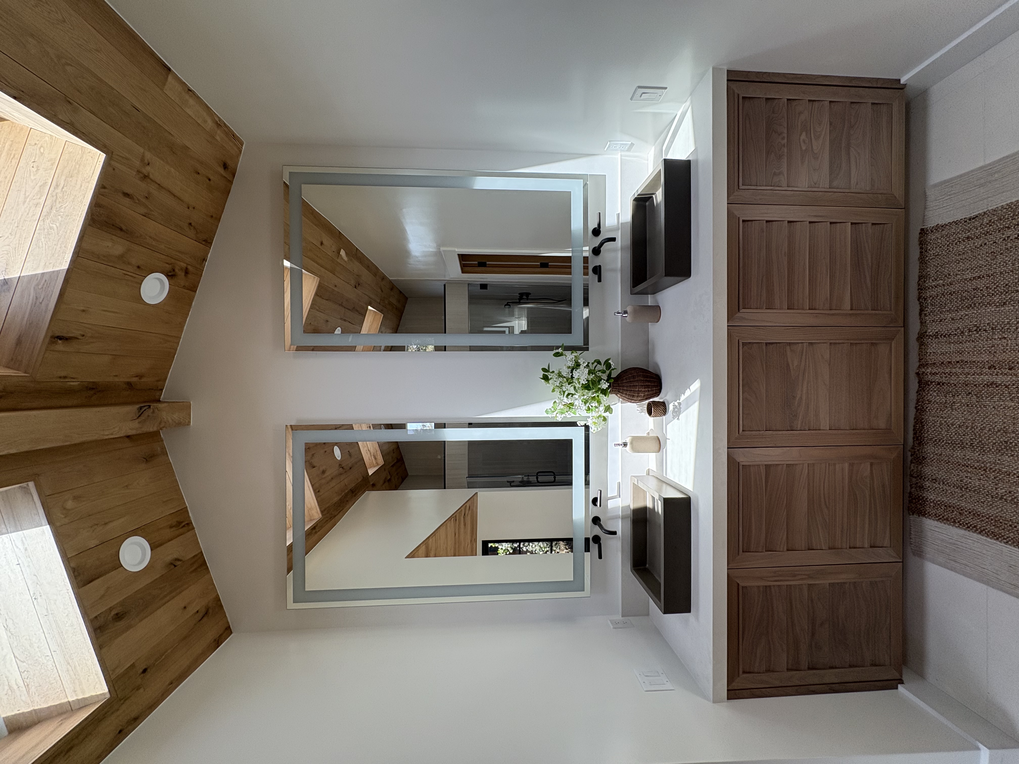 Modern bathroom with dual frameless mirrors, cedar accent wall, walnut cabinetry, and matte black fixtures